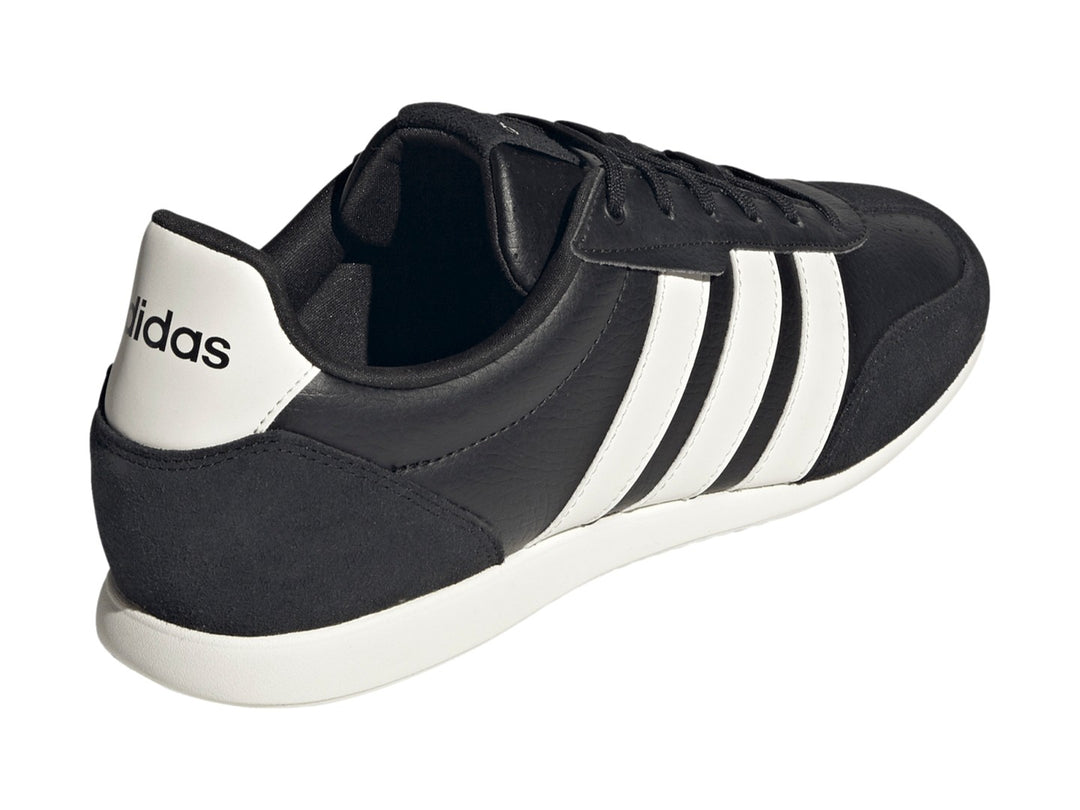 Tenis Adidas Barreda color negro con tres franjas blancas laterales y suela blanca.