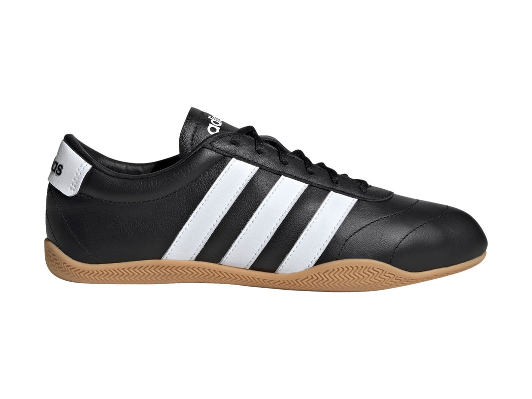 Tenis Adidas Grand Court LO color negro con tres franjas blancas y suela de goma color caramelo.