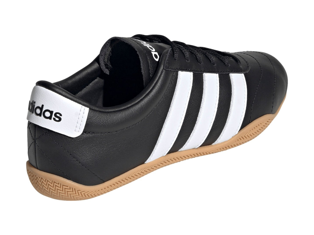 Tenis Adidas Grand Court LO color negro con tres franjas blancas y suela de goma color caramelo.
