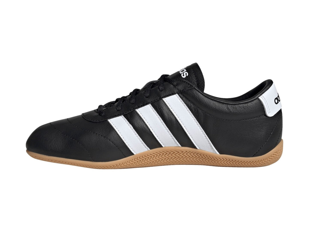Tenis Adidas Grand Court LO color negro con tres franjas blancas y suela de goma color caramelo.