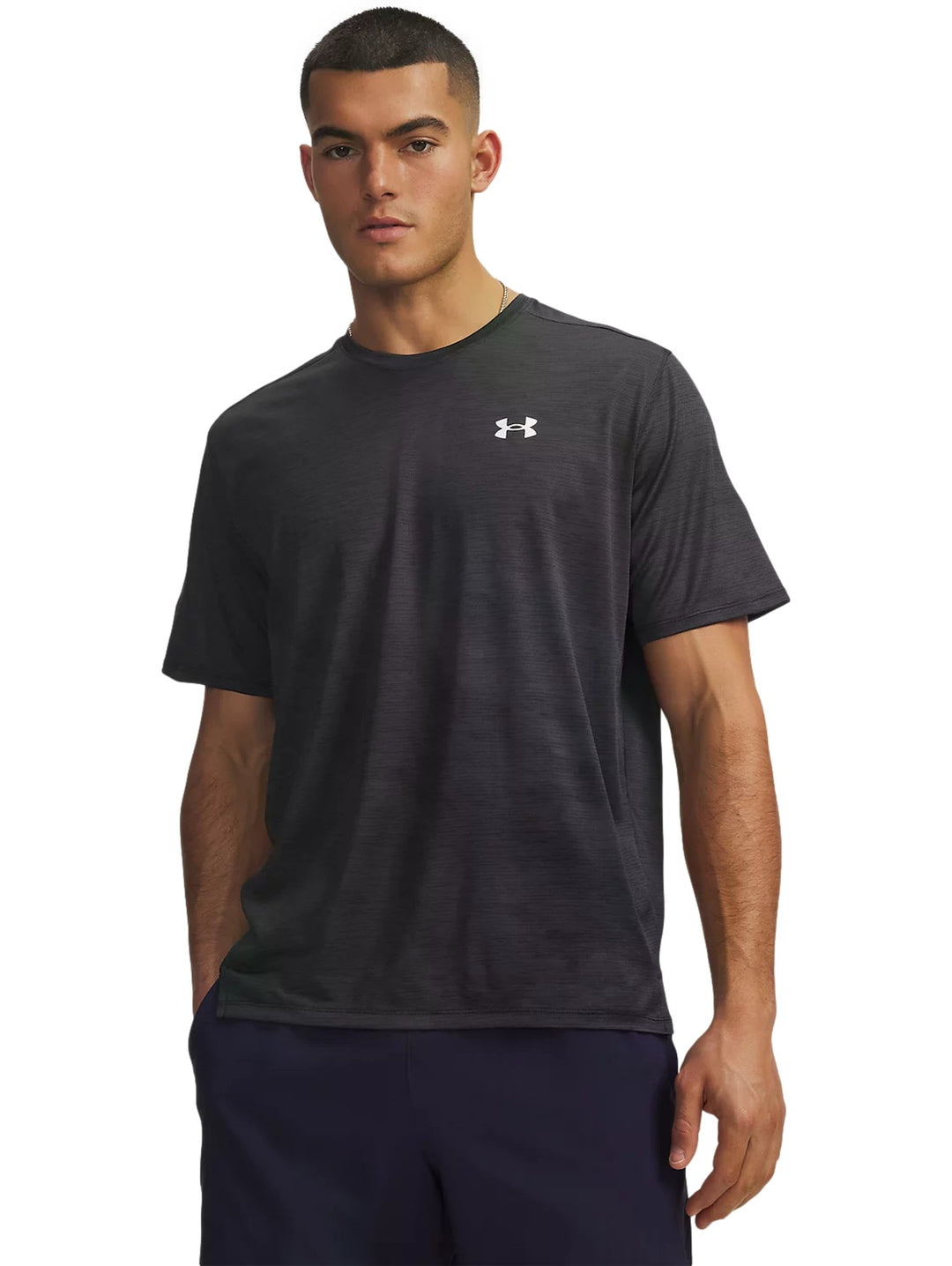 Hombre vistiendo playera deportiva Under Armour Tech Vent de color negro con logotipo blanco en el pecho.