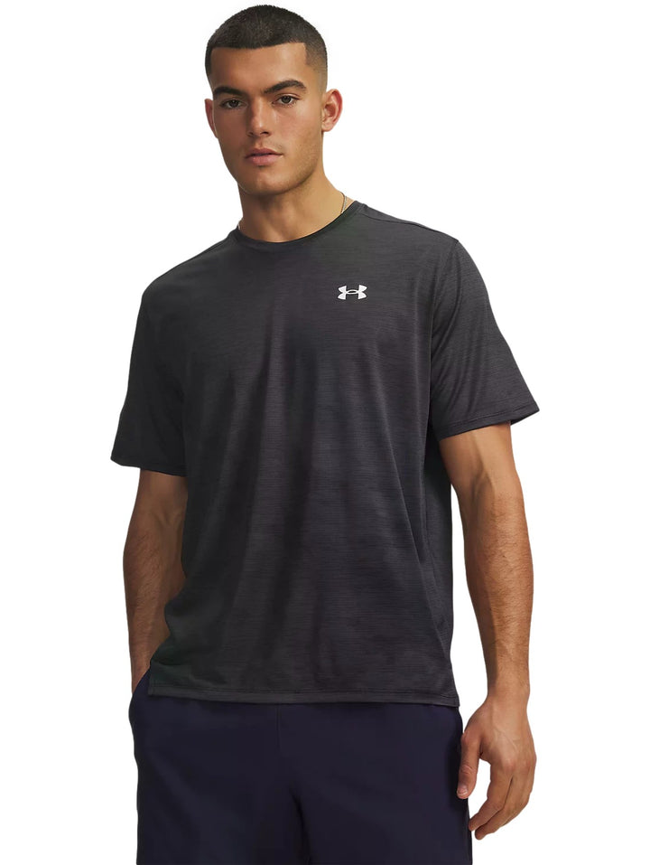 Hombre vistiendo playera deportiva Under Armour Tech Vent de color negro con logotipo blanco en el pecho.