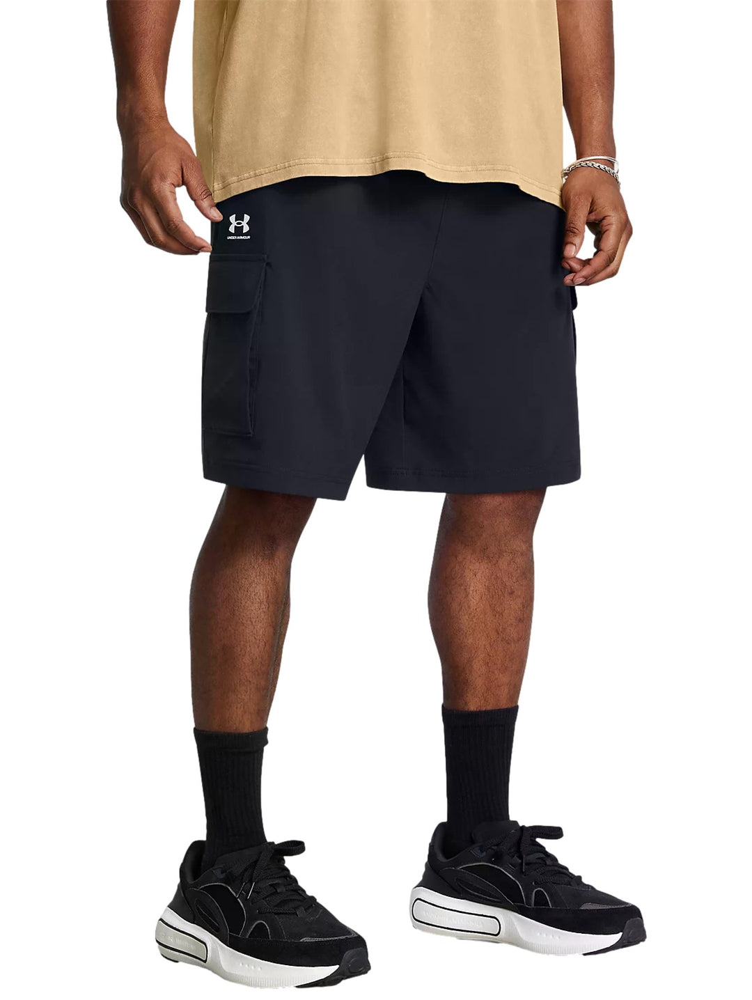 Hombre vistiendo short Under Armour Vibe Cargo color negro con bolsillos laterales y logo blanco.