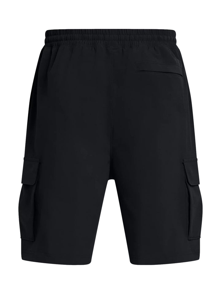 Hombre vistiendo short Under Armour Vibe Cargo color negro con bolsillos laterales y logo blanco.