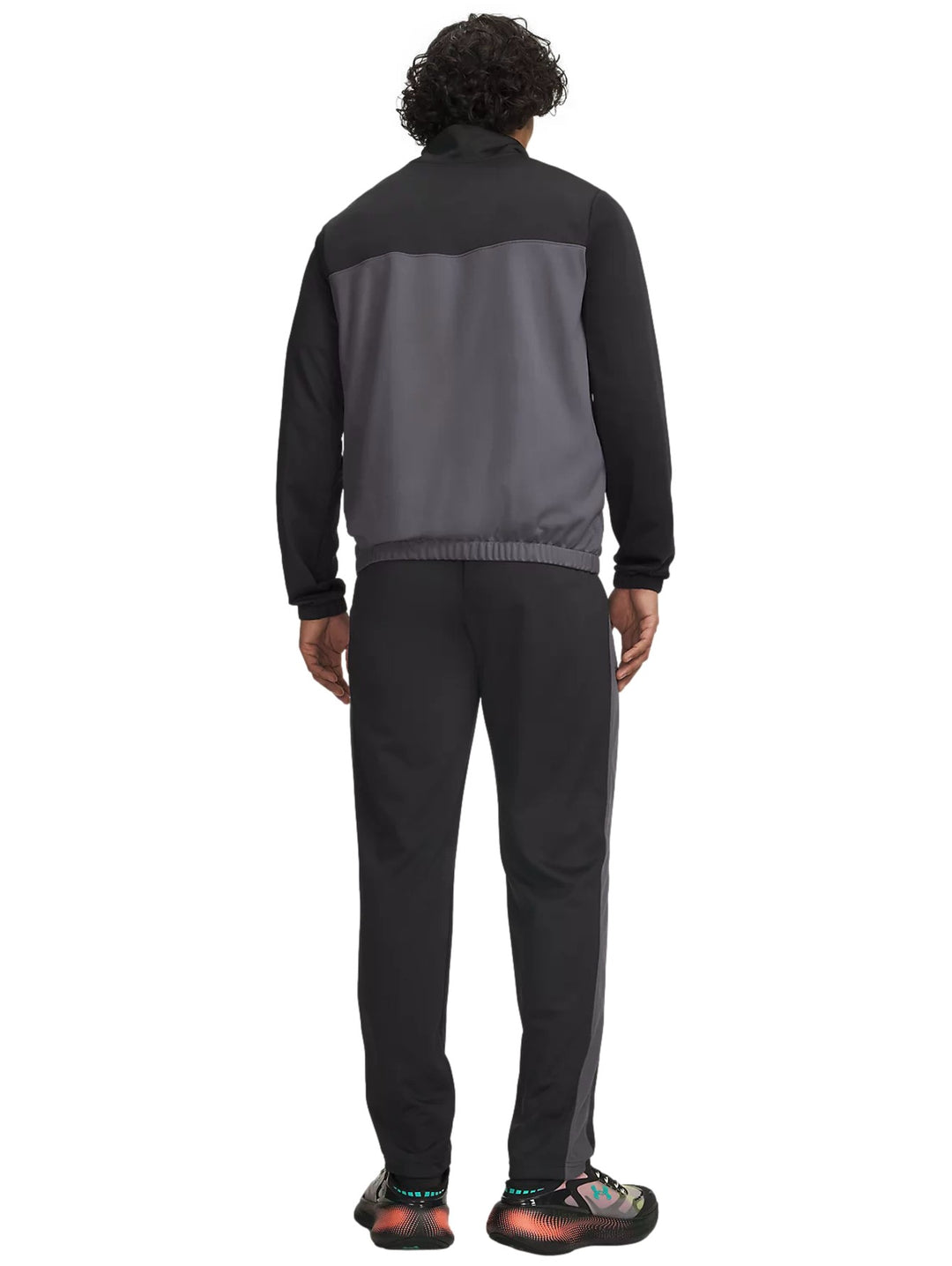 Hombre vistiendo conjunto deportivo Under Armour negro y gris con camiseta blanca y gorra negra.
