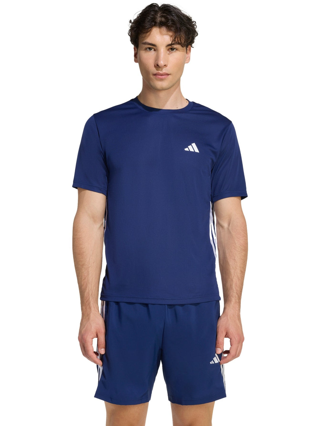 Hombre vistiendo conjunto deportivo Adidas azul marino compuesto por camiseta y shorts con detalles en blanco.