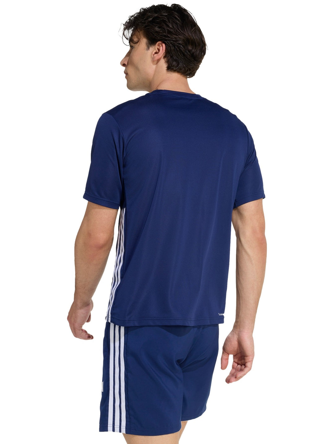 Hombre vistiendo conjunto deportivo Adidas azul marino compuesto por camiseta y shorts con detalles en blanco.