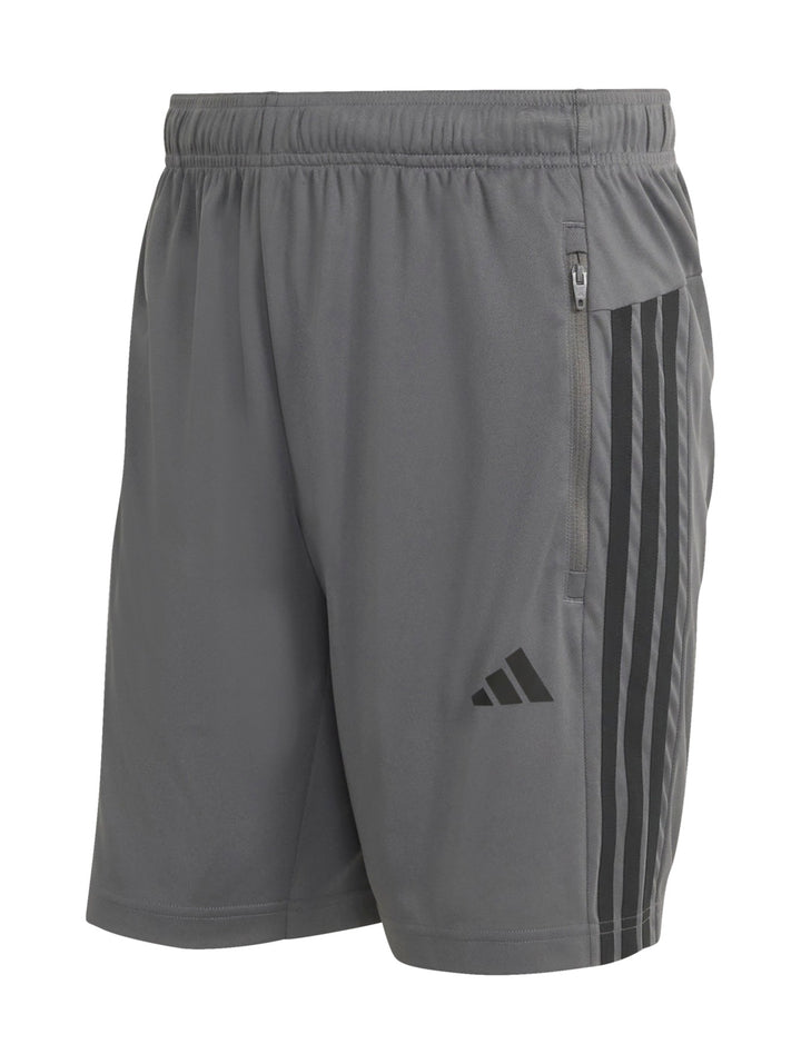 Hombre vistiendo short deportivo Adidas color gris con tres franjas negras laterales y logo frontal.