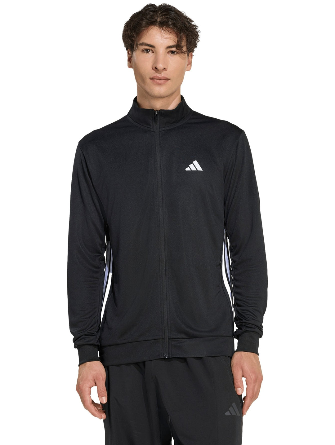 Hombre vistiendo chaqueta deportiva Adidas color negro con detalles blancos y cierre frontal completo.