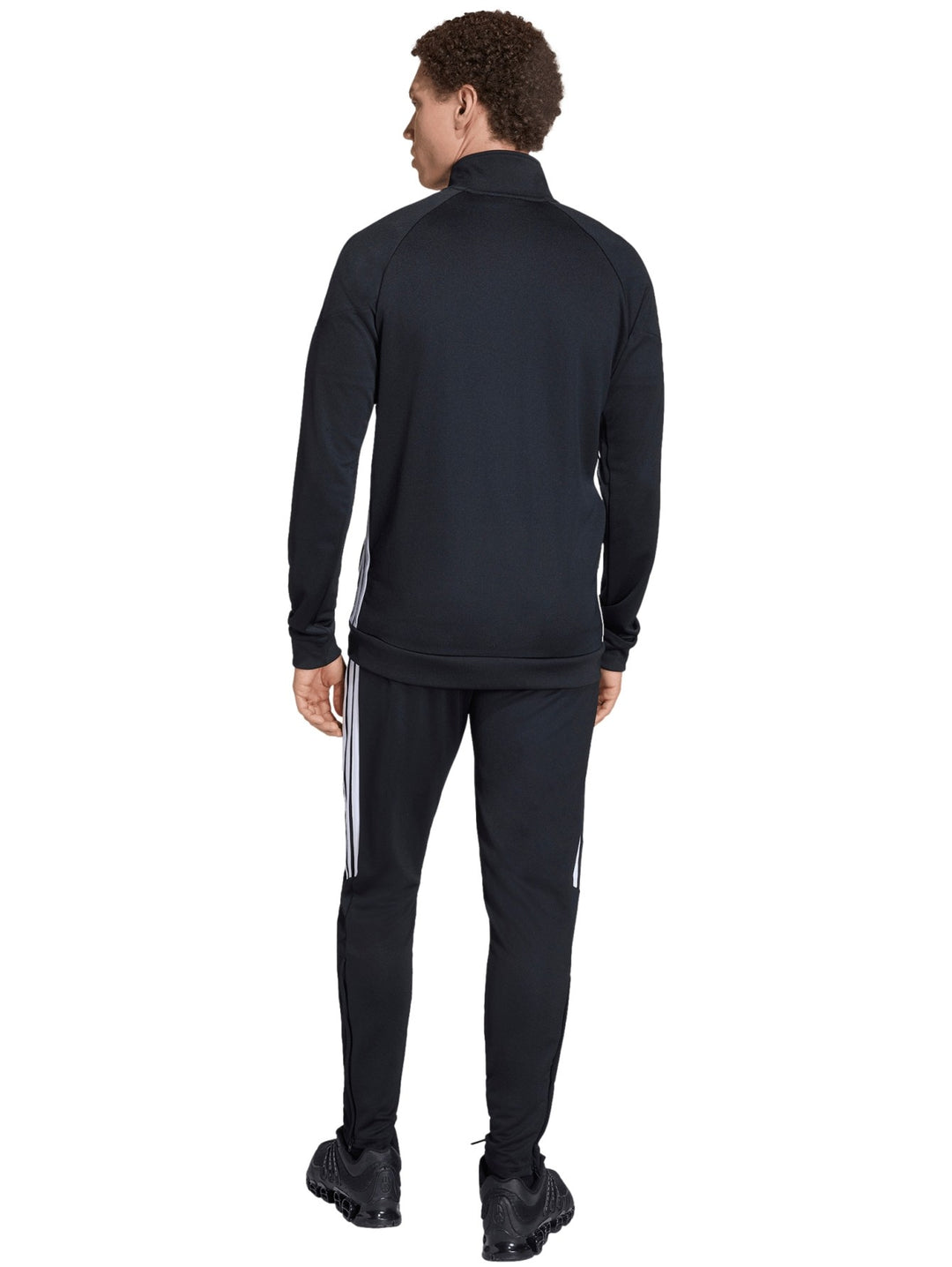 Hombre vistiendo conjunto deportivo Adidas Tiro en color negro con detalles blancos en los costados.