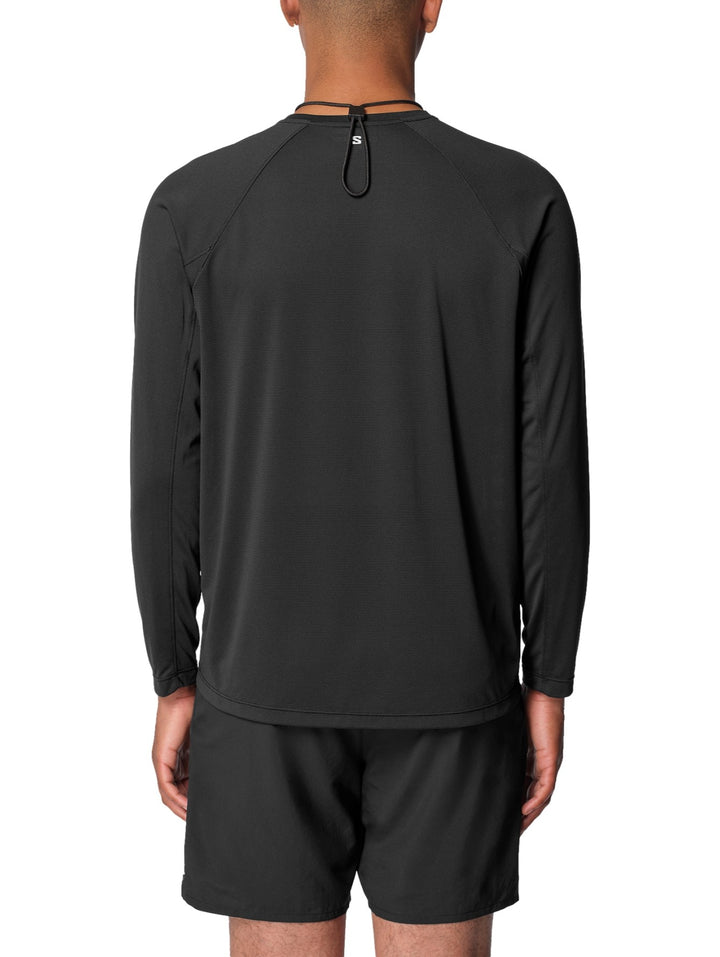 Hombre vistiendo playera deportiva Salomon Shakeout Core de manga larga en color negro.