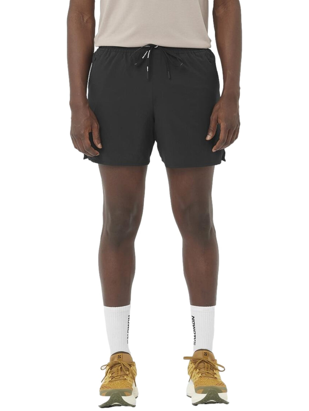 Hombre vistiendo short deportivo Salomon Shakeout Core 5 en color negro con cordón ajustable en la cintura.