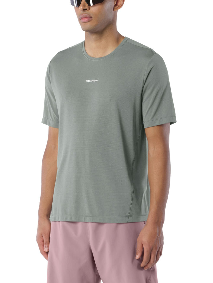 Hombre vistiendo playera deportiva Salomon Shakeout Core en color gris castor con cuello redondo y manga corta.