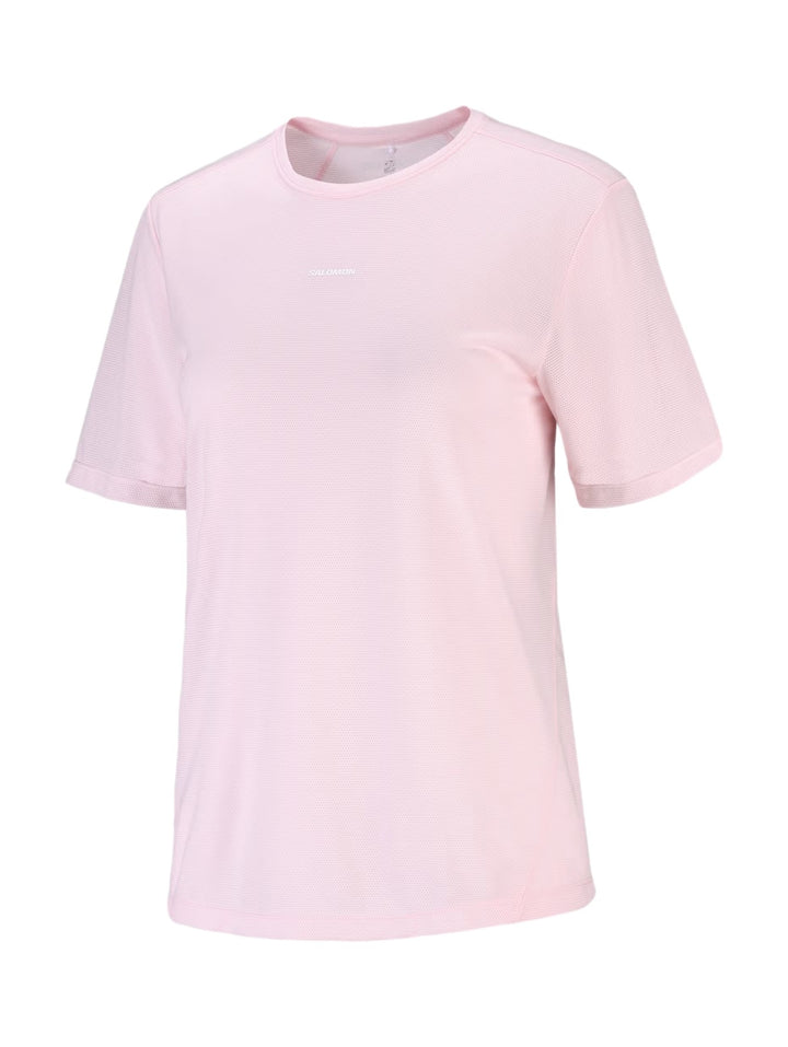 Mujer vistiendo playera deportiva Salomon Shakeout Core en color rosa pálido con tejido transpirable.