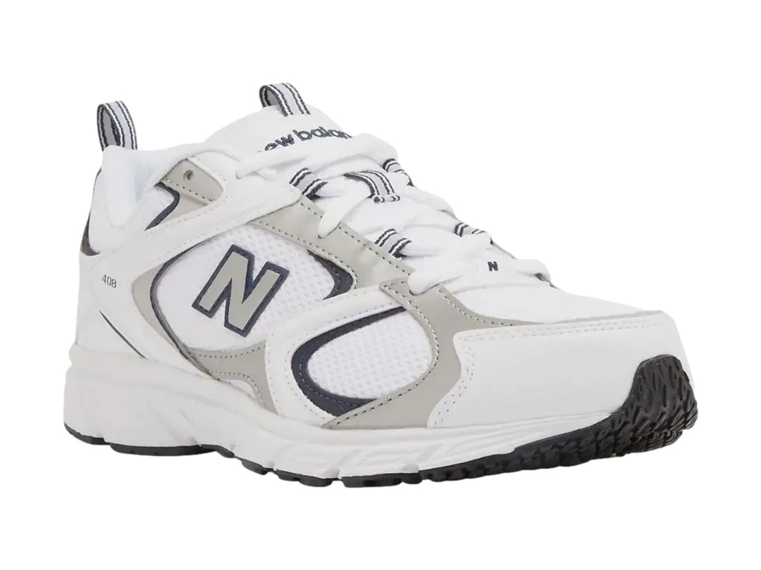 Tenis New Balance 408 color blanco con detalles en gris y azul marino, vista lateral sobre fondo blanco.