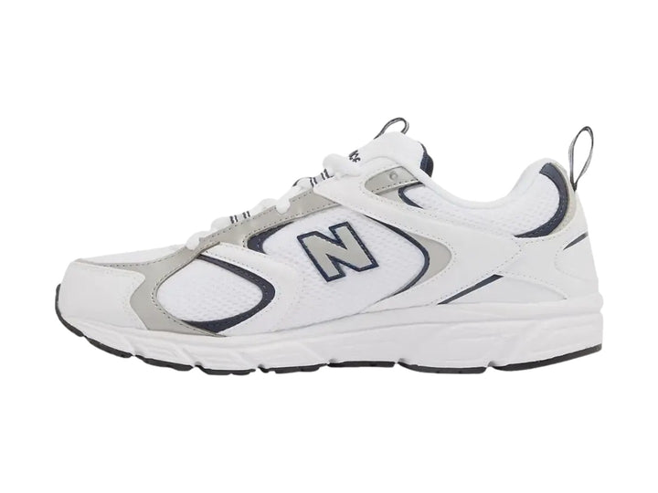 Tenis New Balance 408 color blanco con detalles en gris y azul marino, vista lateral sobre fondo blanco.