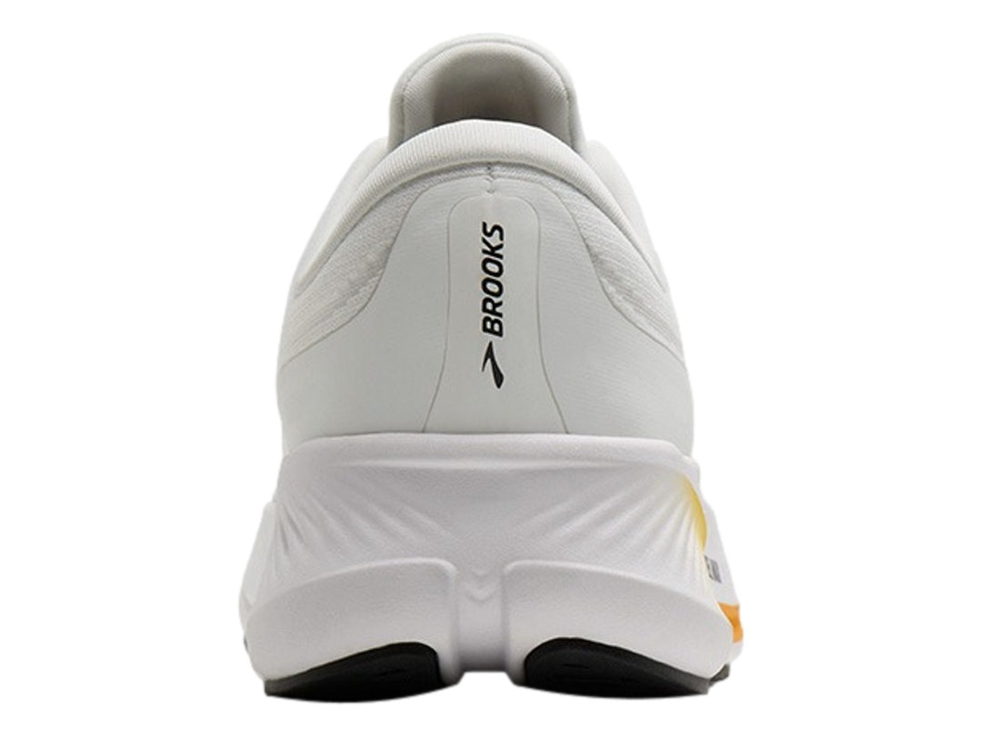 Tenis Brooks Revel Max en color blanco con detalles en naranja y negro, vista lateral sobre fondo blanco.