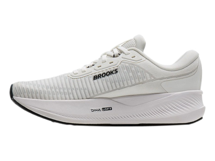 Tenis Brooks Revel Max en color blanco con detalles en naranja y negro, vista lateral sobre fondo blanco.